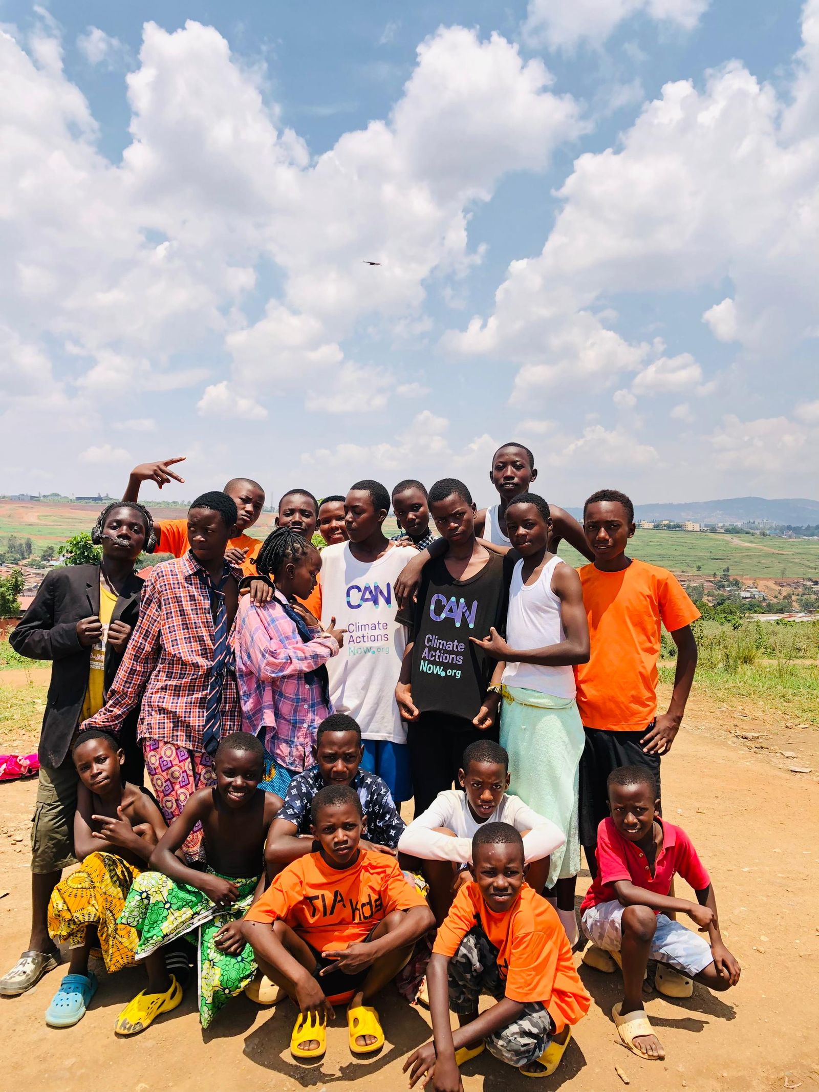 The full CCF and Tia Kids crew on a Kigali hilltop, two boys in front wearing Climate Actions Now t-shirts.