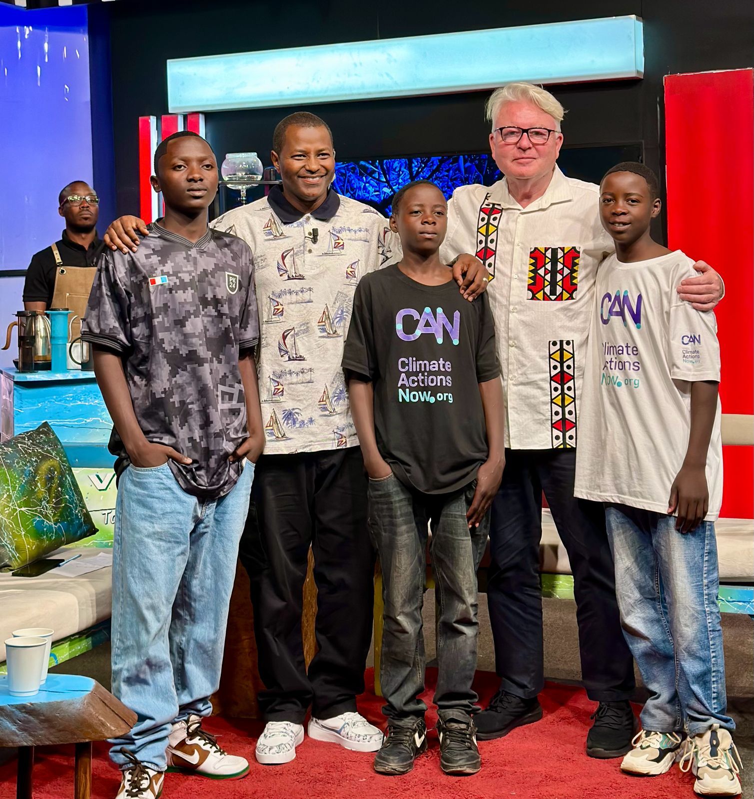 Patron Robert Stephenson with young academy members in CAN t-shirts on a television studio set in Kigali.